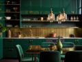 A kitchen designed around green cabinetry, chairs, and a green urn trimmed with brass.